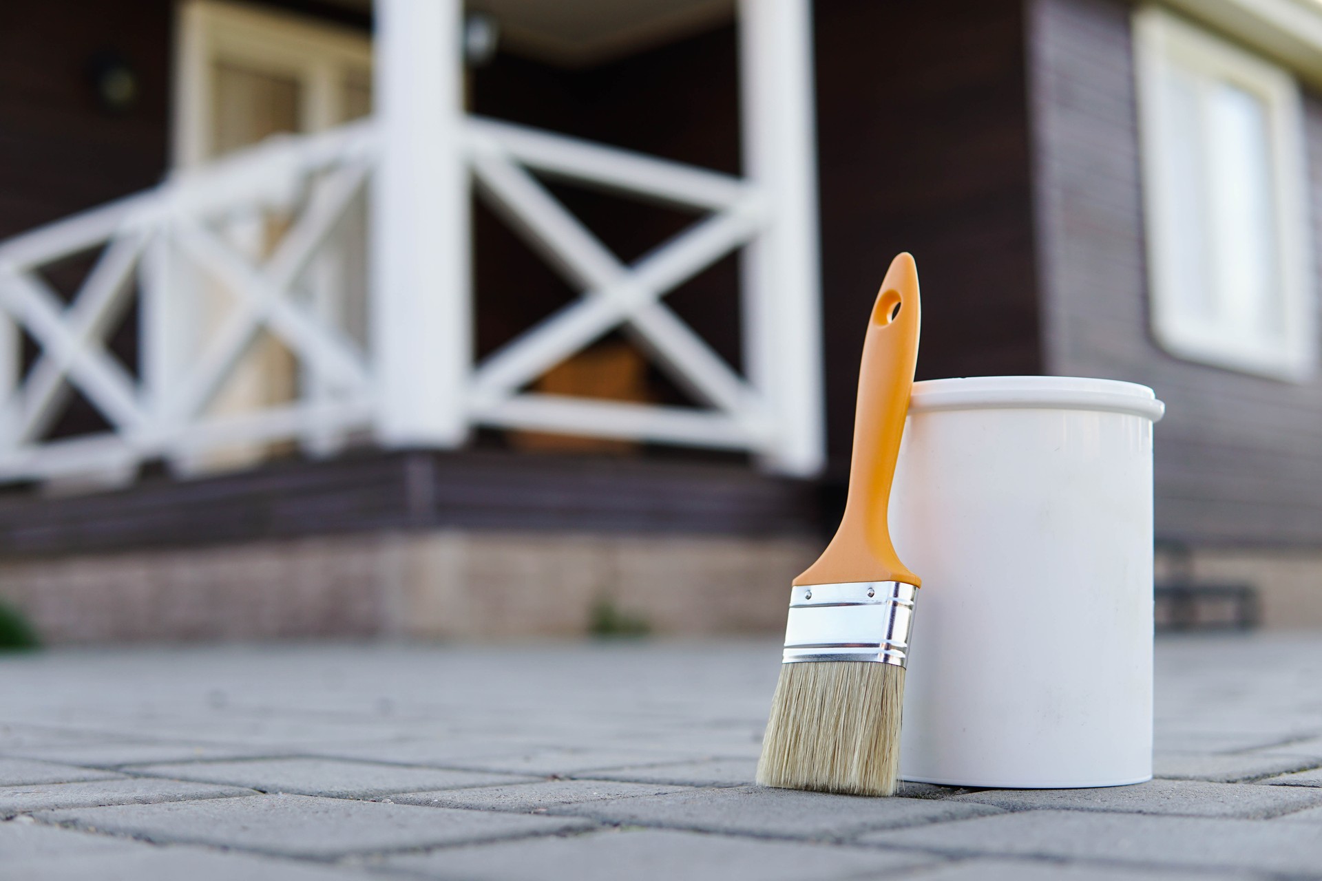 White paint and paint brush. Painted terrace on the background.